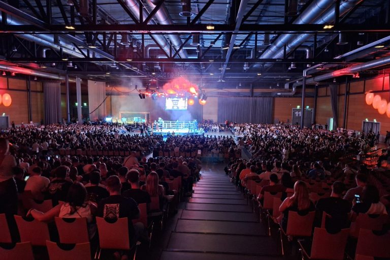 Bild der Champions Fight Night 2025 Große Menschenmenge in einer Halle während einer Veranstaltung, mit Bühnenbeleuchtung.